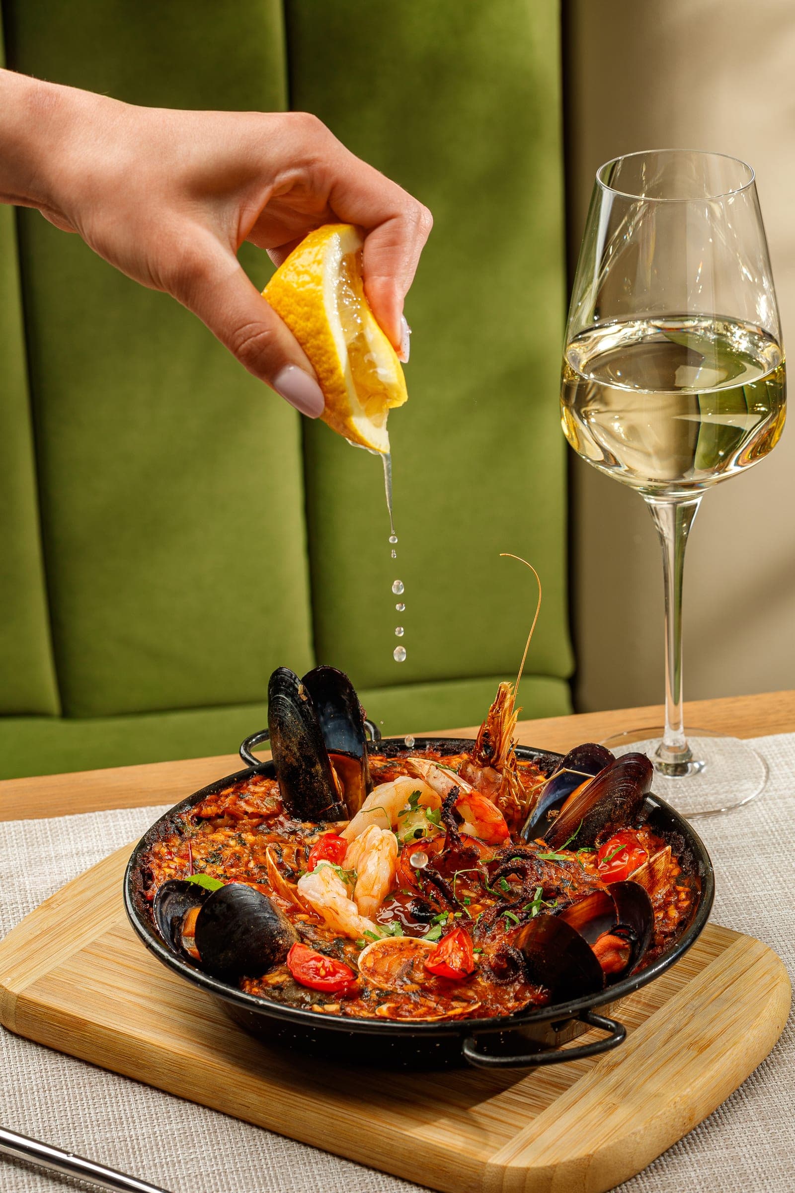Lemon squeezed over a seafood paella on Reina's green banquette
